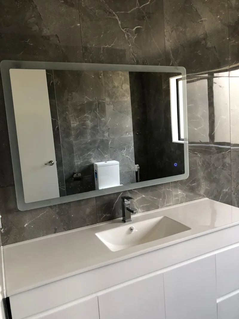 White vanity and mirrored cabinet with dark stone-look bathroom tiling from our project work