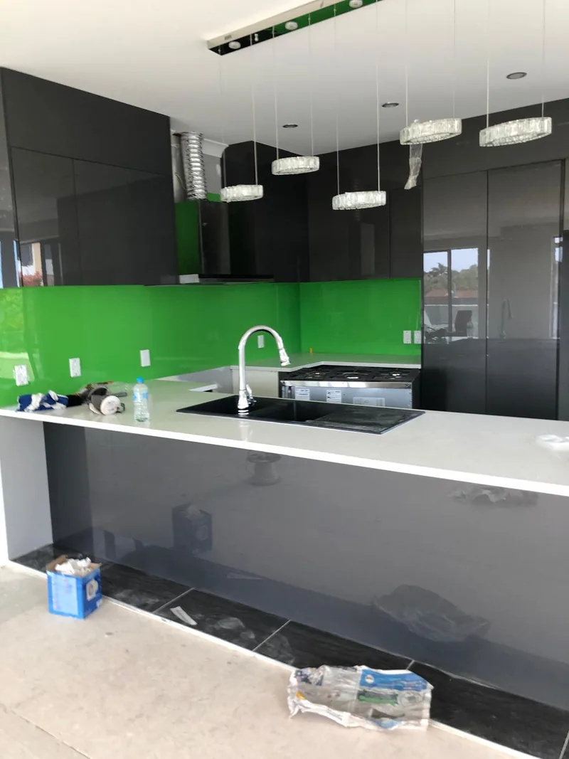 Kitchen renovation in progress with dark cabinets, white benchtop and green splashback