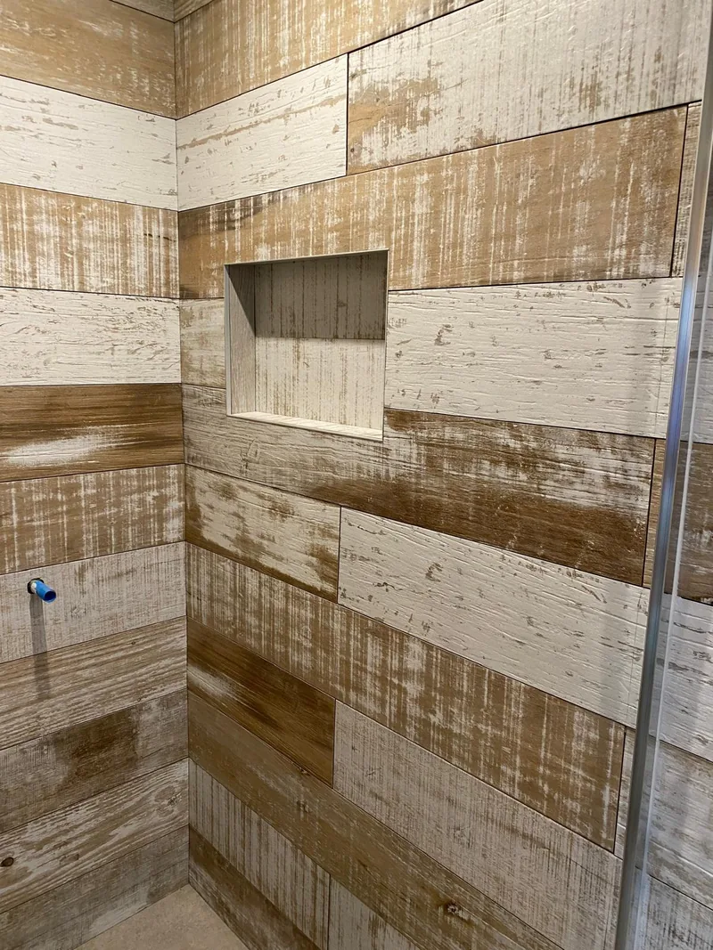 Built-in shower niche surrounded by varied timber-look tiles