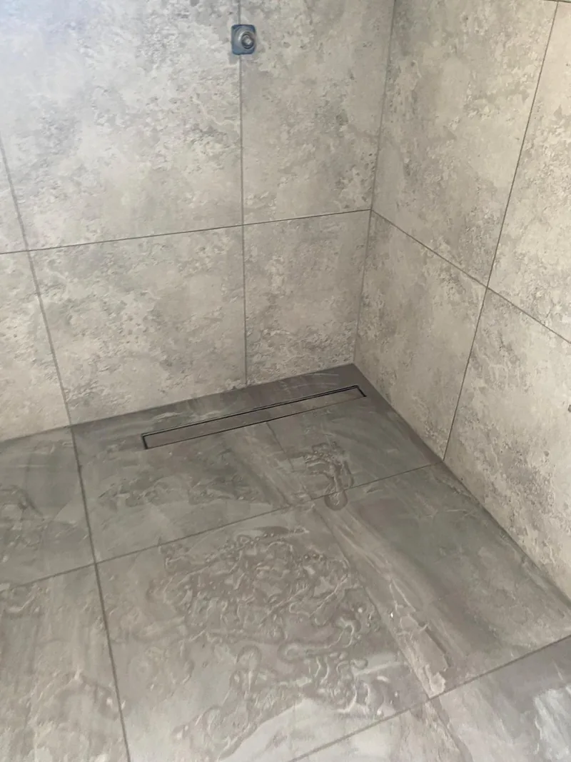 Grey tiled shower floor with a linear drain during installation