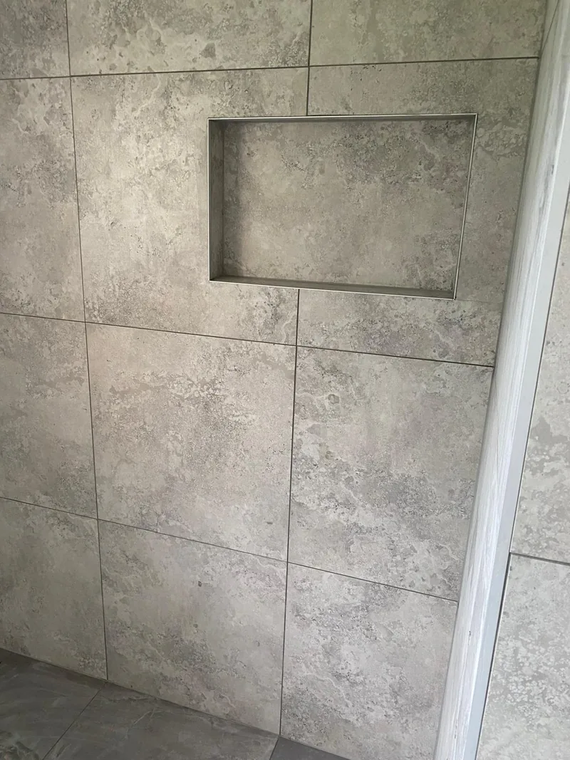 Recessed shower niche set into large grey wall tiles during installation