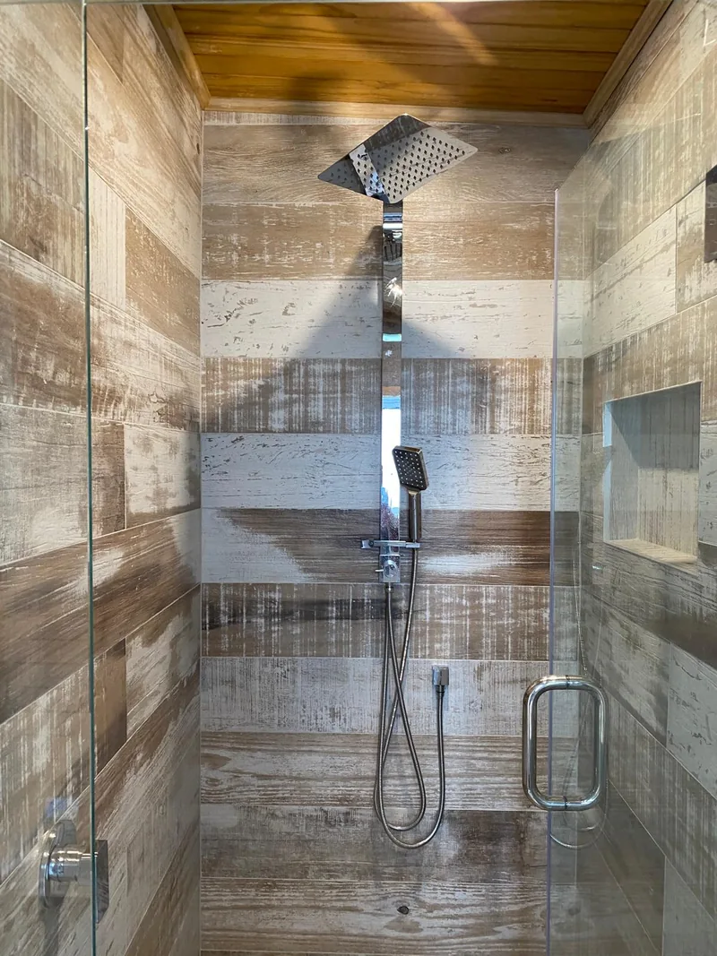 Completed shower with timber-look wall tiles, glass door and rainfall shower head